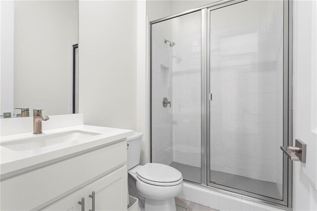 bathroom with toilet, a stall shower, and vanity