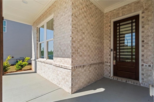 doorway to property with brick siding and a porch