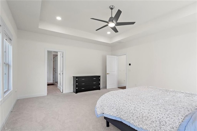 bedroom with recessed lighting, a tray ceiling, and light colored carpet