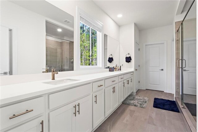 full bath featuring a shower stall, recessed lighting, double vanity, and a sink