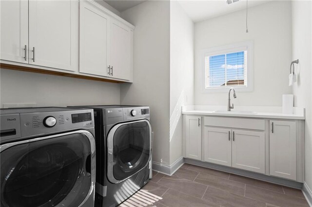laundry room with baseboards, visible vents, cabinet space, washer and dryer, and a sink
