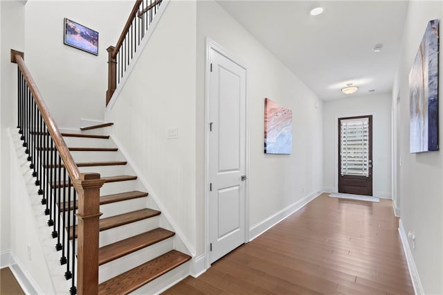 foyer with stairway, baseboards, and wood finished floors