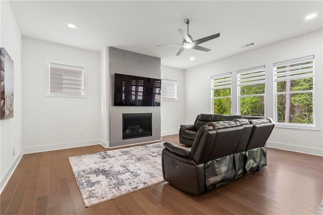 living area featuring ceiling fan, a fireplace, dark wood-type flooring, recessed lighting, and baseboards
