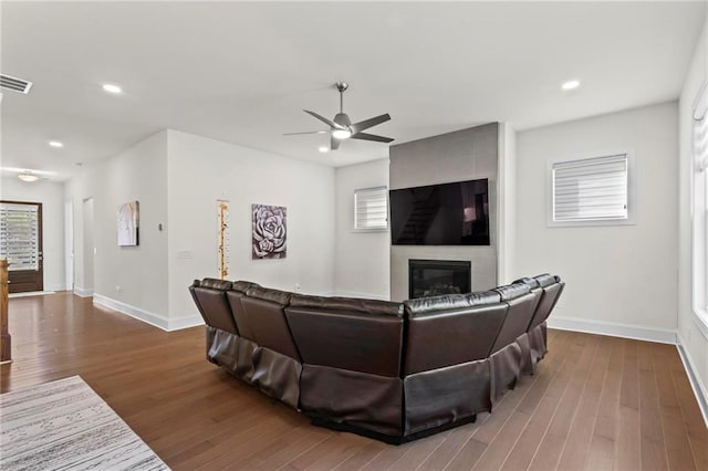 living room featuring wood finished floors, a fireplace, a ceiling fan, and baseboards