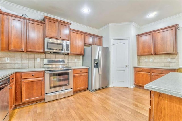 kitchen with light wood-type flooring, stainless steel appliances, brown cabinetry, and light countertops