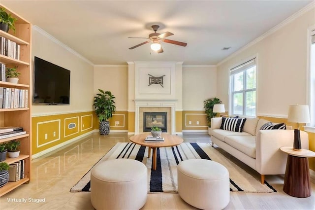 living room with visible vents, crown molding, a fireplace, a decorative wall, and a ceiling fan