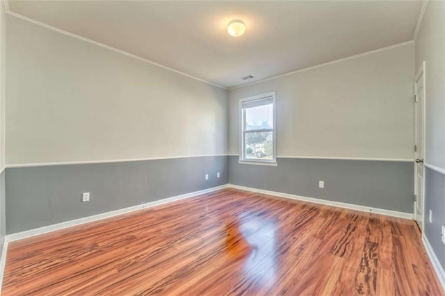 spare room with ornamental molding, baseboards, and wood finished floors