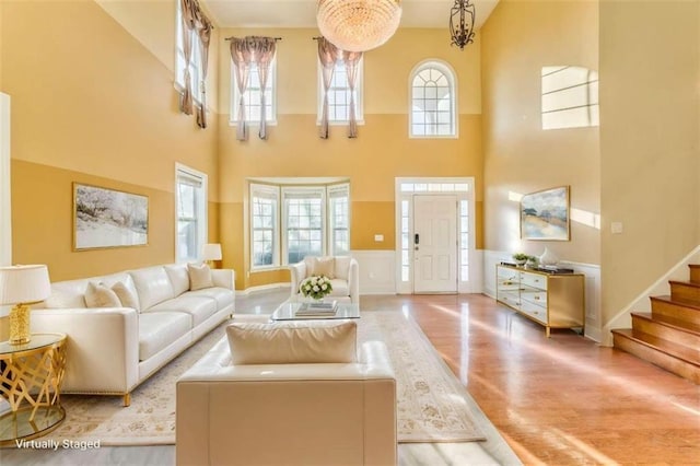 living room with stairway, wainscoting, a healthy amount of sunlight, and wood finished floors