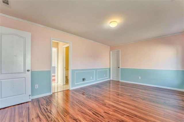 empty room with visible vents, wood finished floors, and crown molding
