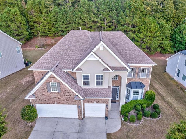 view of front of house featuring brick siding, stucco siding, concrete driveway, and a garage