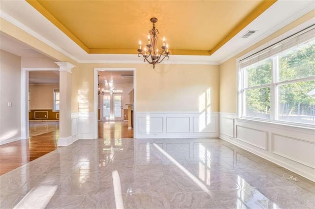 unfurnished room with a raised ceiling, a notable chandelier, and a decorative wall