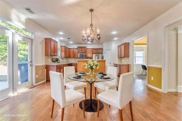 dining area featuring baseboards, visible vents, an inviting chandelier, ornamental molding, and light wood-style floors