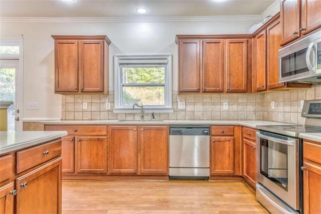 kitchen with a sink, appliances with stainless steel finishes, crown molding, and light countertops