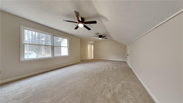 unfurnished room featuring light carpet, visible vents, baseboards, lofted ceiling, and a textured ceiling