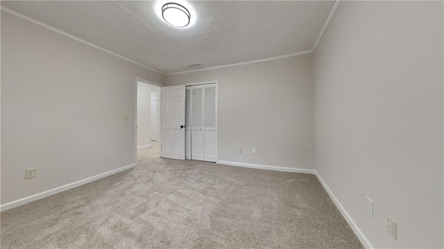 interior space with a textured ceiling, carpet flooring, baseboards, ornamental molding, and a closet