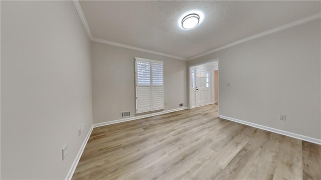 unfurnished room featuring light wood-style floors, baseboards, a textured ceiling, and ornamental molding