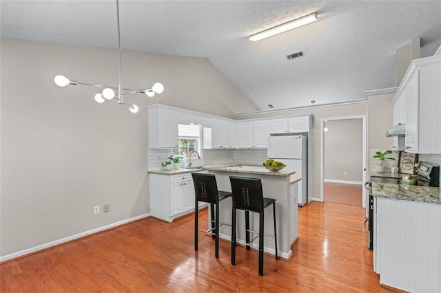 kitchen with stainless steel range with electric stovetop, a kitchen island, tasteful backsplash, a sink, and white cabinets