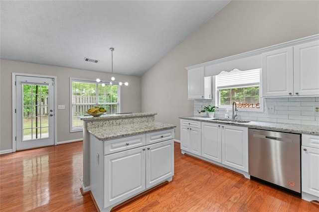 kitchen featuring dishwasher, a sink, light wood-type flooring, vaulted ceiling, and backsplash