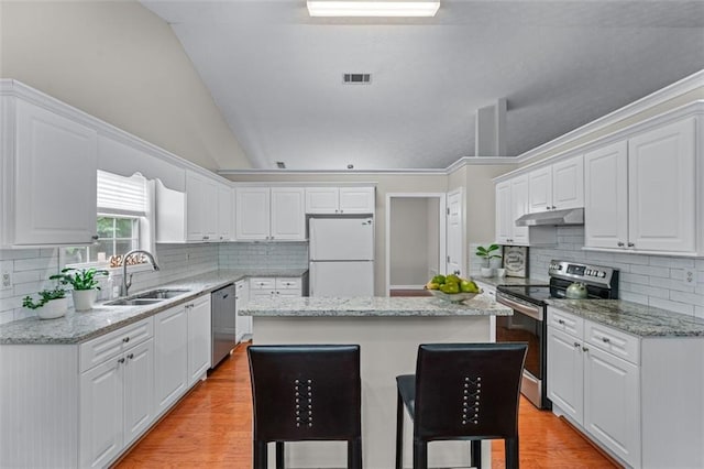 kitchen featuring appliances with stainless steel finishes, under cabinet range hood, a sink, a kitchen island, and light wood-type flooring