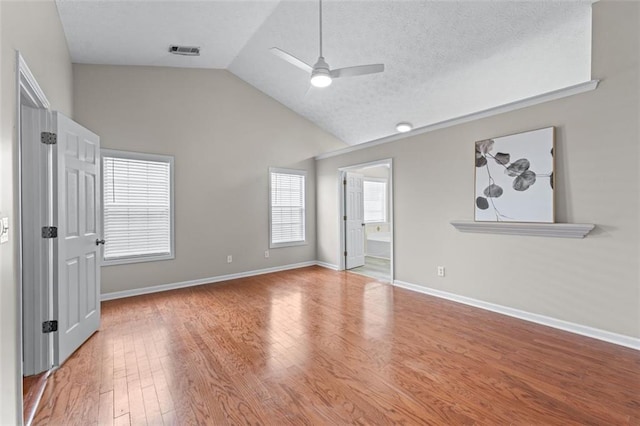 empty room with ceiling fan, wood finished floors, high vaulted ceiling, baseboards, and a textured ceiling