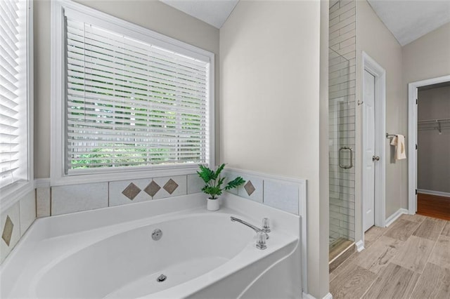 full bathroom with a garden tub, a stall shower, wood finished floors, and a spacious closet