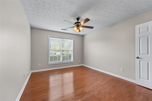 spare room with a ceiling fan, wood finished floors, baseboards, and a textured ceiling