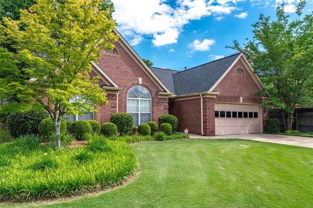 view of front of property featuring brick siding, a front lawn, an attached garage, and roof with shingles