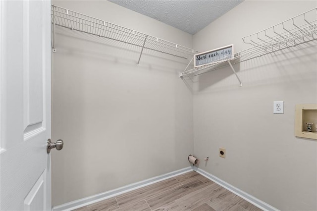 clothes washing area featuring electric dryer hookup, hookup for a gas dryer, hookup for a washing machine, wood finished floors, and baseboards