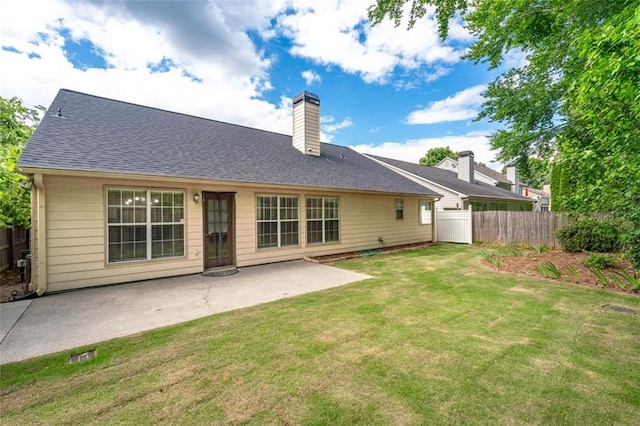 rear view of house featuring a patio area, a chimney, and a shingled roof