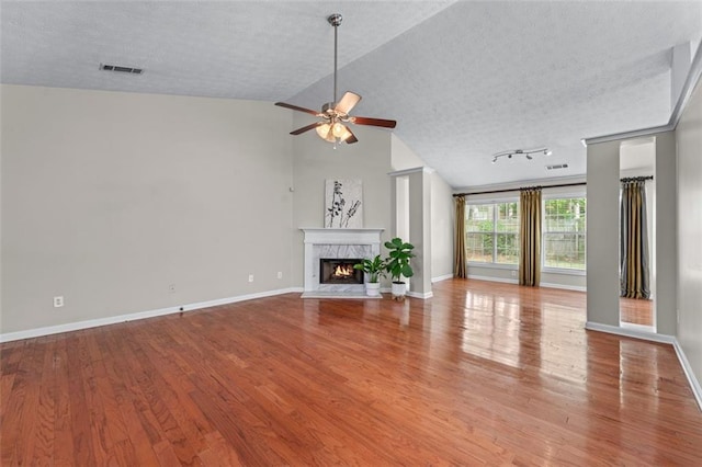 unfurnished living room with a ceiling fan, wood finished floors, a premium fireplace, a textured ceiling, and baseboards