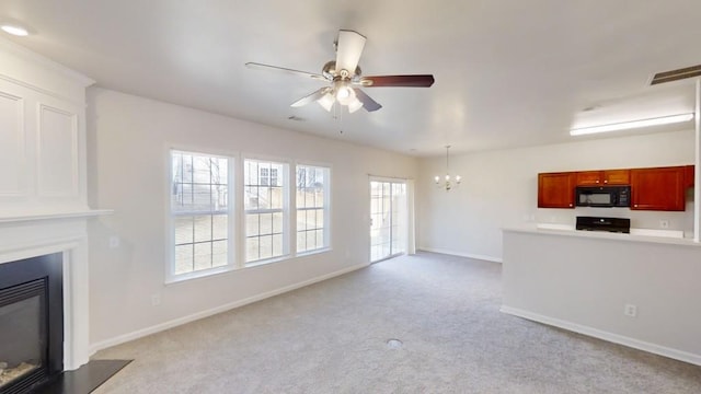 unfurnished living room featuring ceiling fan with notable chandelier and light colored carpet