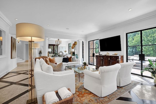 living room with an inviting chandelier, decorative columns, ornamental molding, and a healthy amount of sunlight