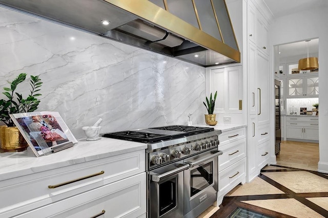 kitchen featuring white cabinets, range with two ovens, light stone counters, and tasteful backsplash