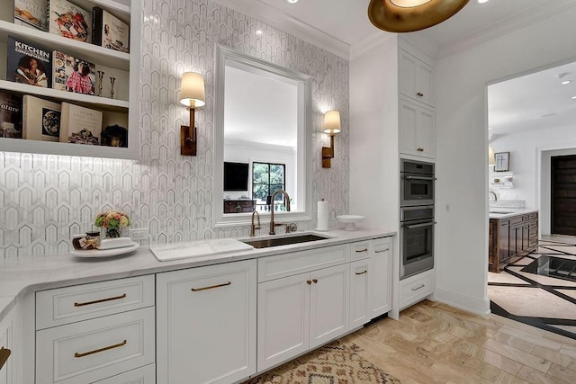 kitchen with double oven, light hardwood / wood-style floors, light stone countertops, white cabinetry, and sink