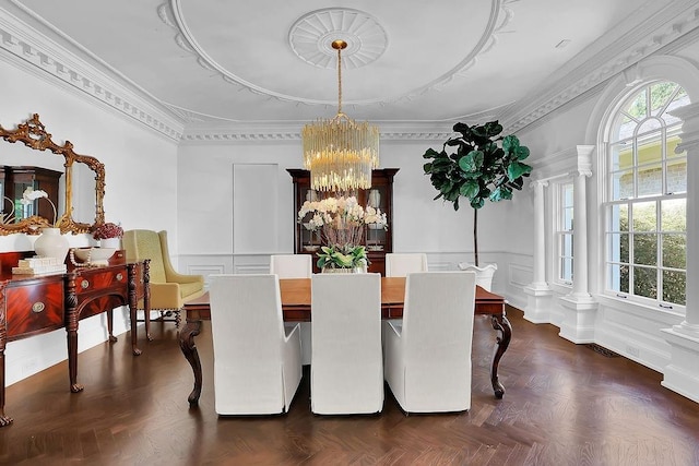 dining room featuring a notable chandelier, dark parquet flooring, crown molding, and ornate columns