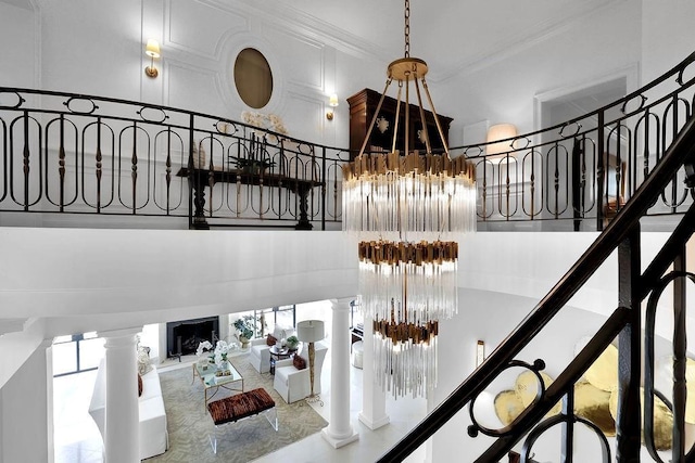 stairway with an inviting chandelier, tile floors, a high ceiling, and ornate columns