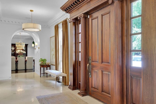 foyer entrance featuring ornamental molding, light tile floors, and an inviting chandelier