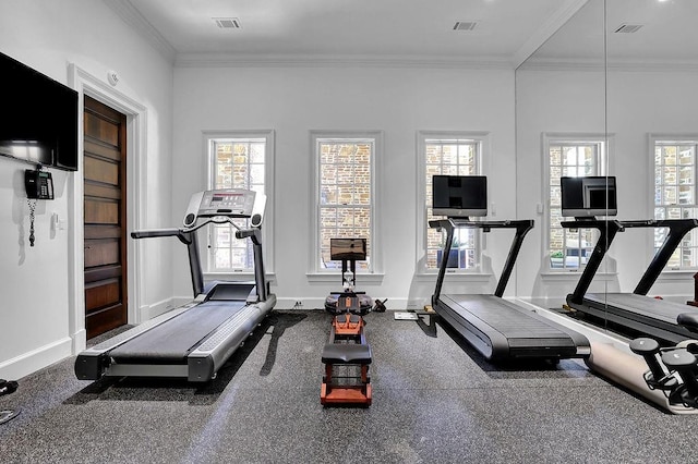 exercise area featuring crown molding, dark colored carpet, and a healthy amount of sunlight