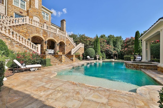 view of swimming pool featuring pool water feature and a patio