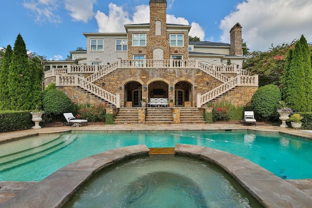 back of house featuring a swimming pool with hot tub