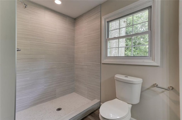 full bathroom featuring toilet, tiled shower, and baseboards