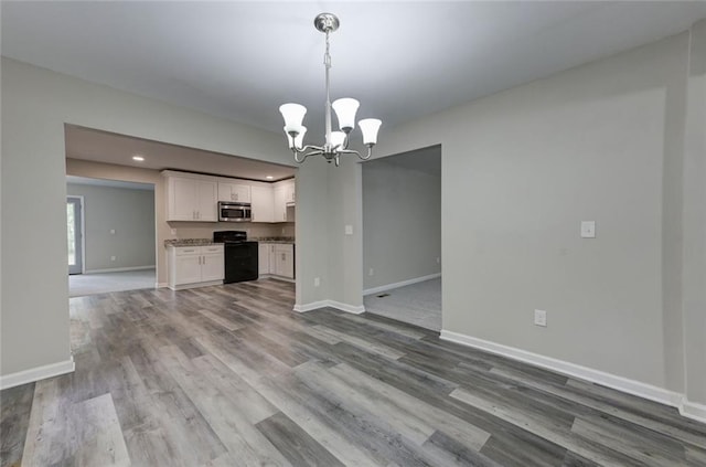 unfurnished living room featuring a chandelier, baseboards, dark wood-style flooring, and recessed lighting