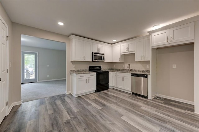 kitchen featuring stainless steel appliances, a sink, baseboards, white cabinetry, and recessed lighting