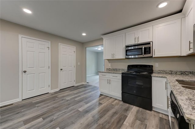 kitchen with appliances with stainless steel finishes, white cabinets, light stone countertops, and recessed lighting