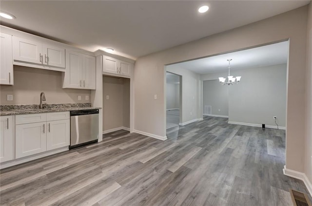 kitchen with stainless steel dishwasher, a sink, light stone counters, light wood-style flooring, and a chandelier