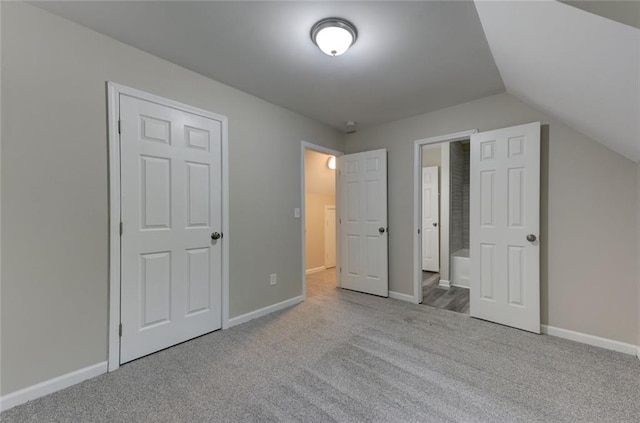 unfurnished bedroom with carpet floors, baseboards, vaulted ceiling, and ensuite bath