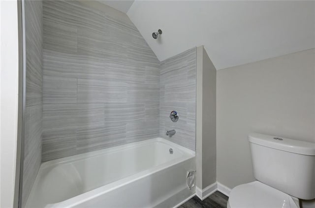 bathroom featuring vaulted ceiling, toilet, a bath, and baseboards