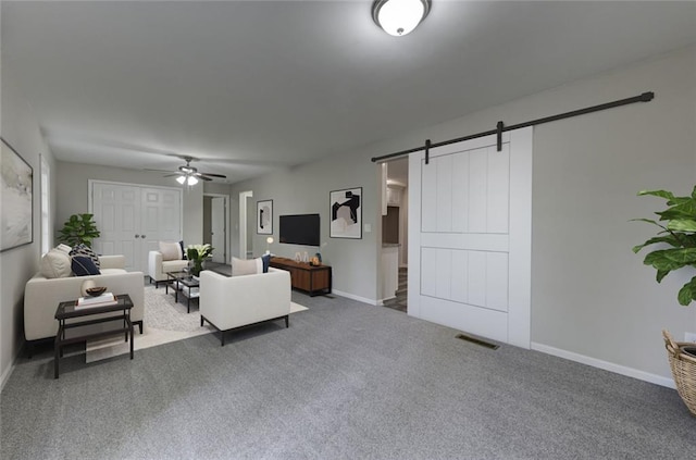 carpeted living room featuring a barn door, a ceiling fan, and baseboards