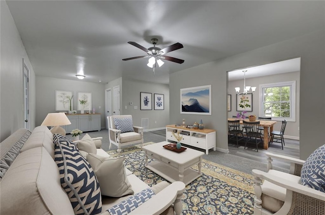 living room featuring baseboards, a chandelier, light colored carpet, and a ceiling fan