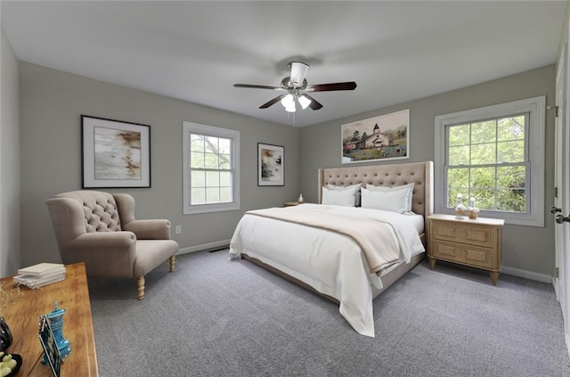 carpeted bedroom featuring multiple windows, baseboards, and a ceiling fan
